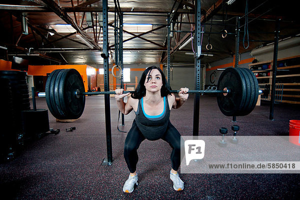 Schwangere junge Frau Gewichtheben mit Langhantel