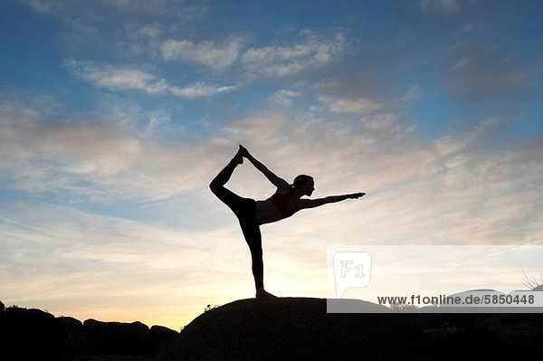 Young woman in dancer pose in desert  silhouette