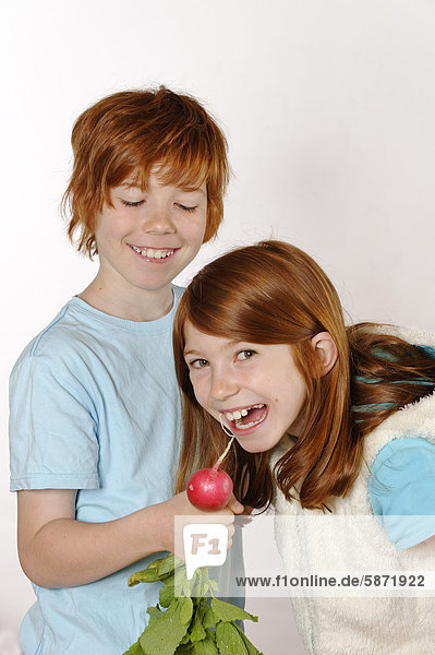 Girl and boy Boy feeding a radish to a girl
