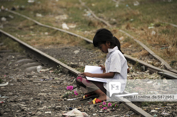 Kambodschanisches Mädchen mit Buch lernt auf einem alten Bahngleis Battambang Kambodscha Asien