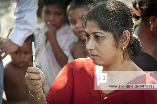 Frau prüft Spritze  bei einer von der Hilfsorganisation Ärzte für die Dritte Welt initiierten Impfaktion oder Impfung für Kinder  bei Kalkutta  Kolkata  Westbengalen  Indien  Asien