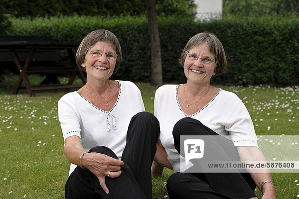 Zwei rüstige Zwillingsschwestern sitzen im Garten