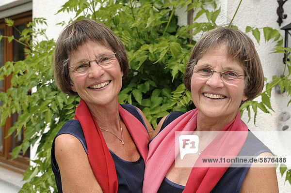 Zwei rüstige Zwillingsschwestern  gleich gekleidet mit roten Schals  Portrait