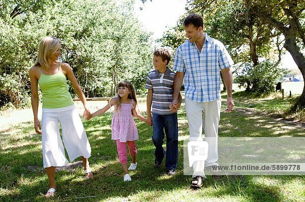 Mid adult couple walking with their two children in a park