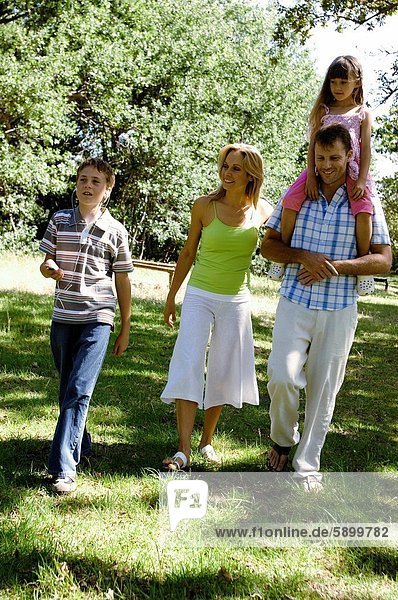 Mid adult couple walking with their two children in a park