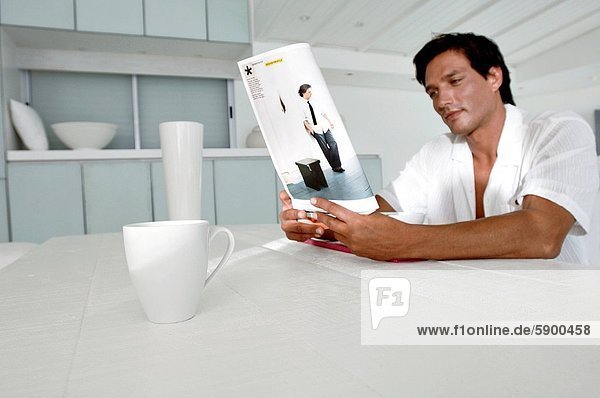 sitzend Mann am Tisch essen Zeitschrift Mittelpunkt Tisch Erwachsener vorlesen