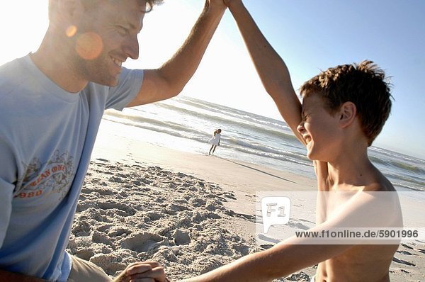 Side profile of a boy playing with his father on the beach