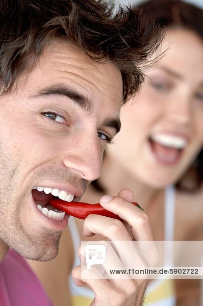 Portrait  Frau  Mann  lächeln  Hintergrund  rot  jung  Peperoni  essen  essend  isst