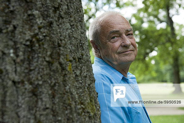 Old man at tree trunk  portrait