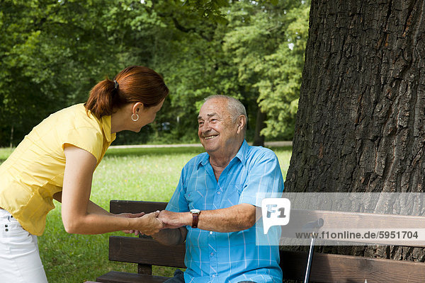 Frau mit einem alten Mann auf einer Parkbank