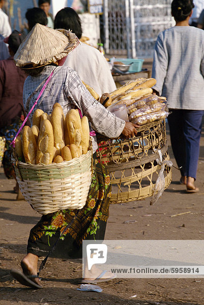 Frau trägt zwei Körbe  französisches Brot in die Talaat Sao in Vientiane  Laos  Indochina  Südostasien  Asien