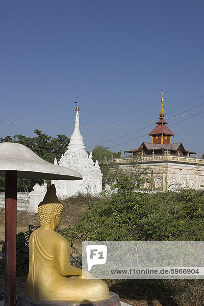 Buddhastatue sitzend unter Sonnenschirm in der Nähe von Pagoden  Salay  Myanmar (Birma)  Asien