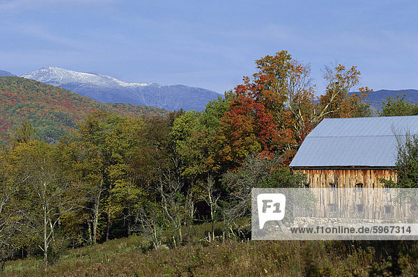 An old wooden farm building and trees in fall colours  with the White Mountains behind  near Jackson  New Hampshire  New England  United States of America  North America