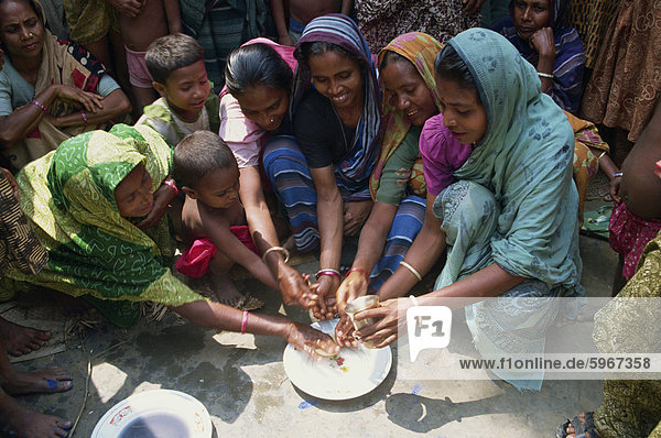 Eine Gruppe von Bangladeshi Frauen und Kinder Händewaschen als Teil eines Systems der Gesundheit Ausbildung in Bangladesch  Asien