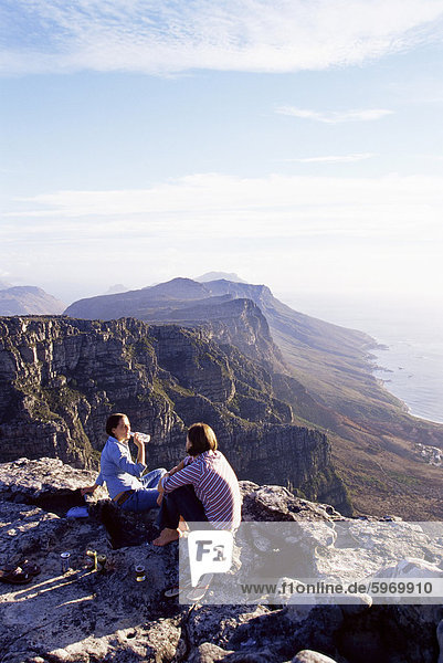 Two women sitting on a cliff on the top of Table Mountain  Cape Town  South Africa  Africa
