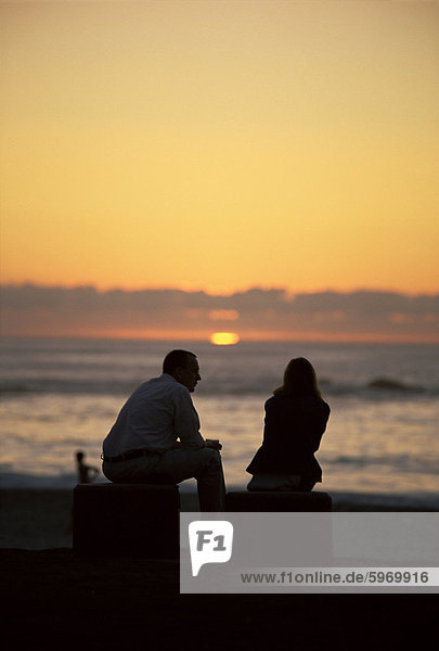 Silhouette of a couple watching the sunset  Camps Bay beach  Cape Town  South Africa  Africa