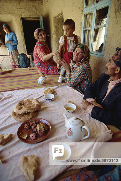 Tadschikische Familie am Tisch mit typischen Angebot von Hammelfleisch  Tee und Brot  in der Nähe von Ayni  Tadschikistan  Zentralasien  Asien