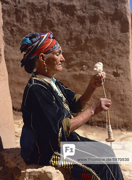 Alte Frau in traditioneller Kleidung  demonstriert wolle Spinnen  indem Spinnrocken  in der Nähe von Ouarzazate  Marokko  Nordafrika  Afrika