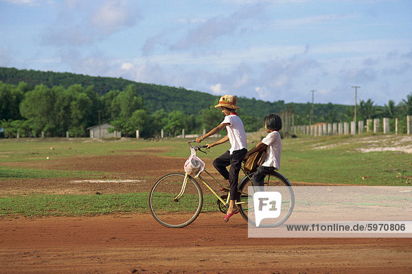 Two children riding on a bicycle through a rural area on Phu Quoc Island in south west Vietnam  Indochina  Southeast Asia  Asia
