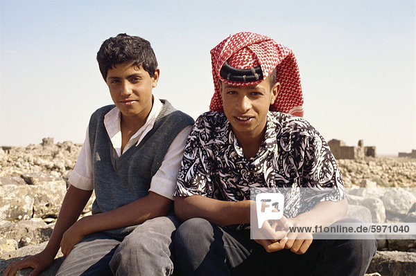 Portrait of two young local guides  one wearing traditional headcloth  at the ruins at Umm al Jimal  Jordan  Middle East