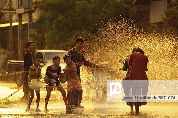 Menschen auf einem Motorrad wird mit Wasser überschüttet  von Männern und jungen während des Songklan-Festivals in Thailand  Südostasien  Asien