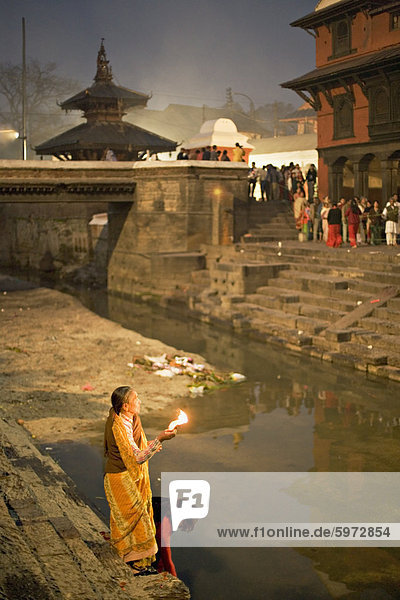 Zwei Frauen darbringen (Puja) vor der Morgendämmerung am Fluss Bagmati außerhalb der Shiva-Tempel während der Hindu-fest Shivaratri  Pashupatinath  Kathmandu  Nepal  Asien