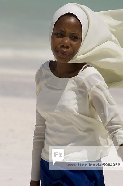 Ein Schulmädchen entlang Kiwendwa Strand trägt einen weißen Kopftuch und blauen Rock  Sansibar  Tansania  Ostafrika  Afrika
