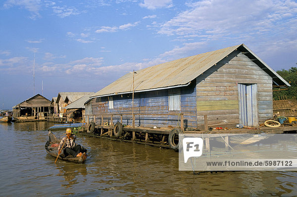 Man in canoe passing a house  floating fishing village of Chong Kneas  Tonle Sap lake  near Siem Reap  Cambodia  Indochina  Southeast Asia  Asia