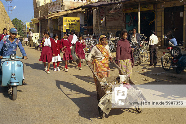 Rubbish collector and school children in street in Jaisalmer  Rajasthan state  India  Asia