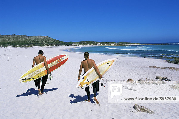 Two surfers walking with their boards on Kommetjie beach  Cape Town  South Africa  Africa