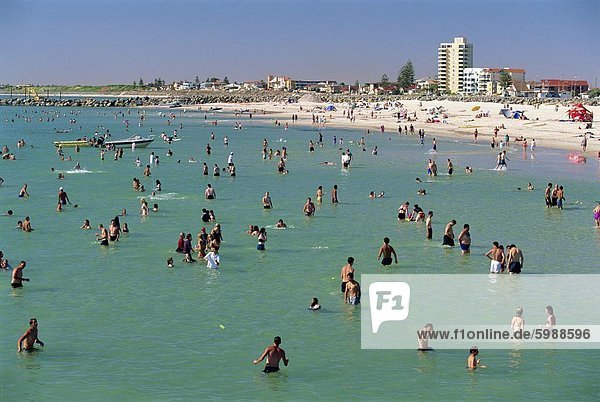 Gruppen von Menschen im Meer und am Strand von Glenelg  einem Resort-Vorort von Adelaide  wo erste South Australian Kolonisten  South Australia  Australien  Pazifik landete