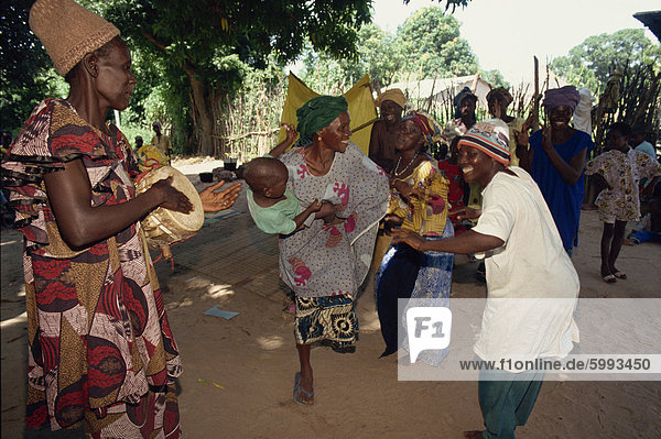 Small group of people  including woman with her baby  dancing outdoors  Gambia  West Africa  Africa