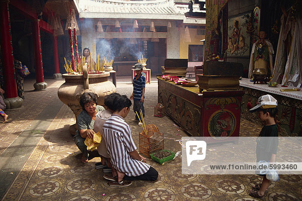 Frauen und Kinder in einem Tempel  mit brennenden Räucherstäbchen hinter  bei Cholon in Vietnam  Indochina  Südostasien  Asien