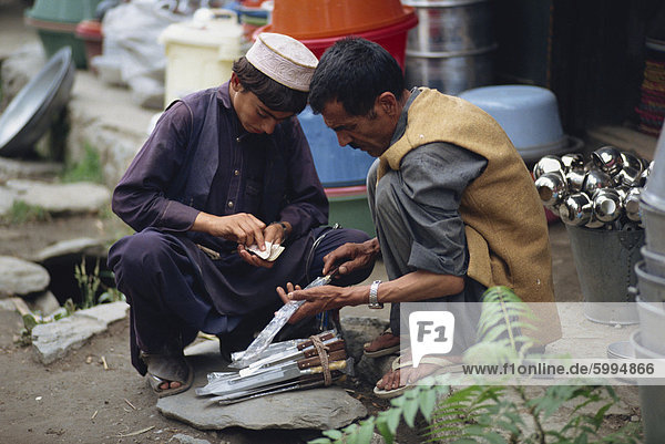 A young man counting his money buying a knife from a street trader in Gilgit  Pakistan  Asia