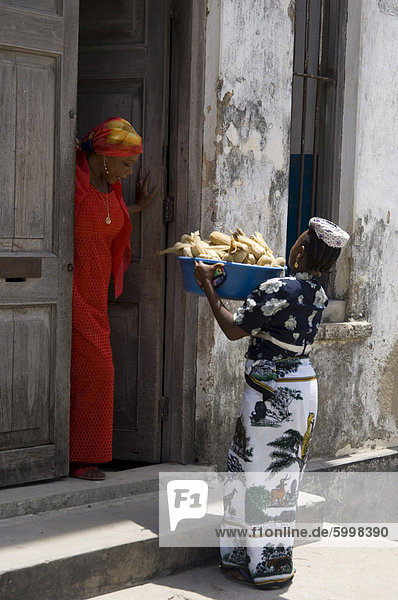 A woman selling corn door to door on a street in Stone Town  Zanzibar  Tanzania  East Africa  Africa