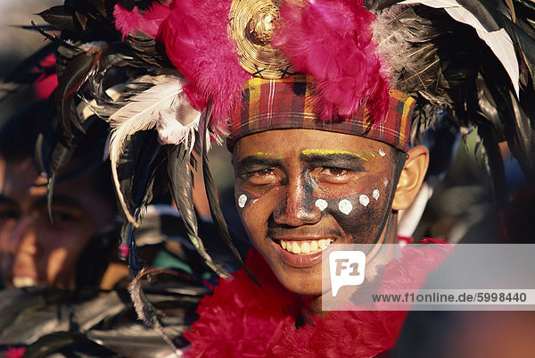 Porträt eines Mannes mit Gesichts Dekoration und Kopf-Kleid mit Federn am Mardi Gras Karneval  Dinagyang in Iloilo City  Insel Panay  Philippinen  Südostasien  Asien