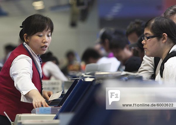A female airline ticket agent issuing a ticket to a travel customer  Beijing  China  Asia