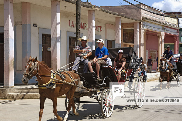 Tourists enjoying a horse-drawn buggy ride through Moron  Ciego de Cvila  Cuba  West Indies  Central America