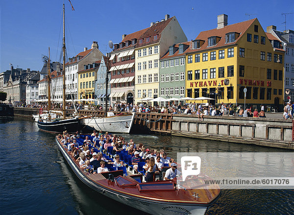 Touristen auf Bootsfahrt übergeben bemalte Gebäuden auf der belebten Uferpromenade von Nyhavn  Kopenhagen  Dänemark  Skandinavien  Europa