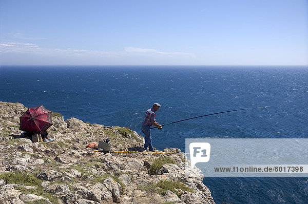 Ein Mann der Fische von den hohen Klippen Cabo de São Vicente  Algarve  Portugal  Europa