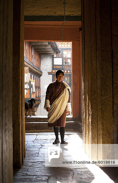 Local man in national dress backlit by evening sunlight at the Jakar Dzong  Jakar  Bumthang  Bhutan  Asia