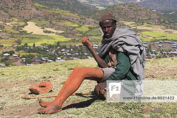 Pilgrim sitting on rock near church with mud on limbs which is thought to have magical healing properties  Lalibela  Ethiopia  Africa