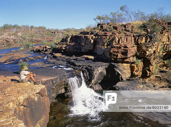 Ein Mann sitzt auf einem Felsen hinauf  auf der ersten Etappe der Mitchell-Wasserfälle in Kimberley  Western Australia  Australien  Pazifik