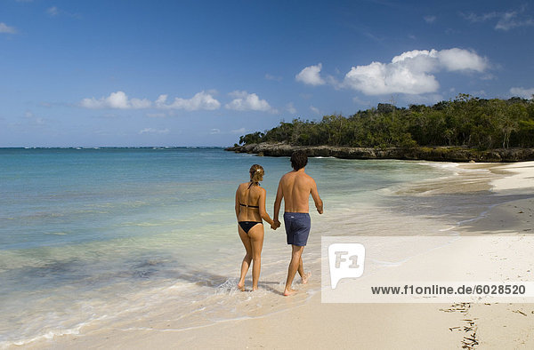A couple walking along a small sandy beach near the Hotel Melia Rio de Oro  Carretera Guardalavaca  Cuba  West Indies  Central America