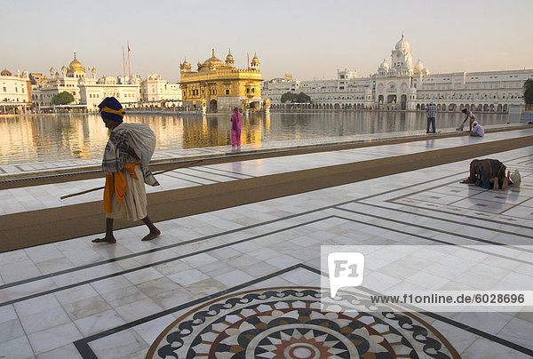 Elderly Sikh pilgrim with bundle and stick walking around holy pool  Golden Temple  Amritsar  Punjab state  India  Asia