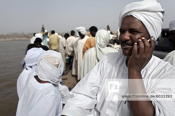 A Sudanese man talks on his mobile phone during a Nile ferry crossing to the town of Dongola  Sudan  Africa