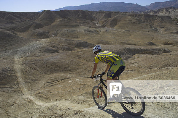 Back view of competitior riding downhill in the Mount Sodom International Mountain Bike Race  Dead Sea area  Israel  Middle East
