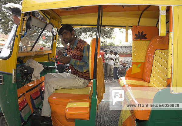Rickshaw owner sitting in his newly decorated moto rickshaw  Agra  Uttar Pradesh state  India  Asia