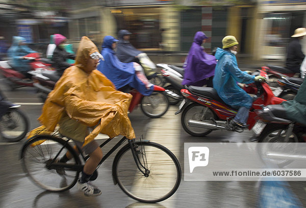 People riding bikes and mopeds in the rain wearing nylon protection  Old Quarter  Hanoi  Vietnam  Indochina  Southeast Asia  Asia
