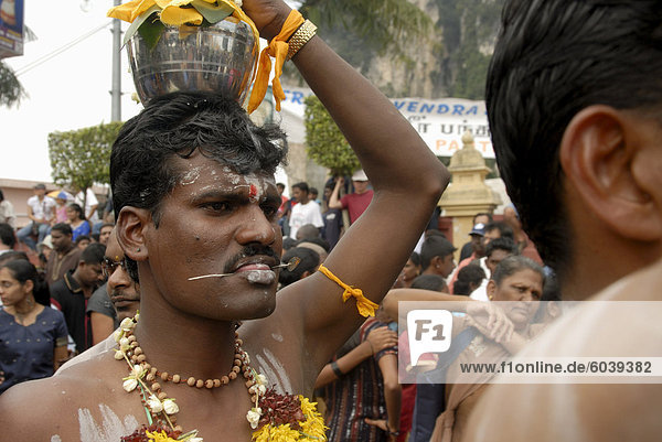 Pilgrim known as kavadi (carrier) with pierced tongue during the Hindu Thaipusam Festival carrying container (paal kudam) of milk offerings from Sri Subramaniyar Swami Temple up to Batu Caves Selangor Malaysia Southeast Asia Asia